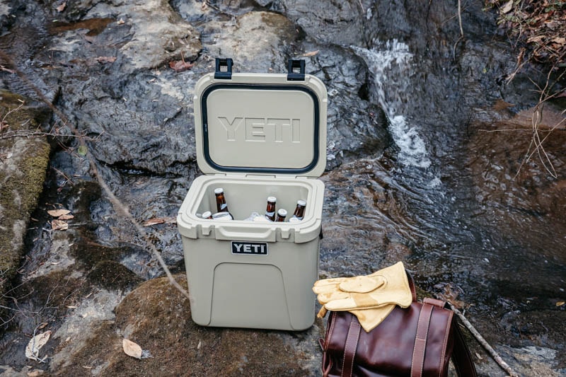 https://coolerspy.com/wp-content/uploads/2022/03/yeti-roadie-24-with-drinks-next-to-bag-and-gloves.jpg